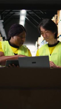 Dikey Video Büyük ölçekli depo ekibi e-ticaret sipariş işlemlerini yönetir, depodaki büyük sanayi raflarına yerleştirilen paketleri kontrol eder. Yeleklerdeki çalışanlar kutulara bakarlar. Kamera A.