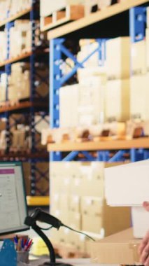 Dikey Video Depo çalışanı kargo paketlerine uygulanan hava yolu etiketlerini tarıyor, paket izleme yazılımındaki nakliye rotasını izliyor. Lojistiğin detaylarını kaydediyorum. Kamera A.