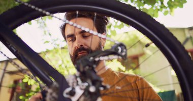 Yakın plan çekimde dışarıdaki kendini adamış beyaz bir genç tarafından bisiklet çarkının incelenip onarıldığını görüyoruz. Motosiklet lastiklerini inceleyen sağlıklı aktif bir adam bahçedeki özel bir aletle hasar tespiti yapıyor..