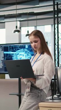 Ofisteki gülümseyen genç kadın programcının dikey video portresi. Yapay zeka senaryoları kullanarak tekrarlanan görevleri otomatikleştiriyor. Neşeli küçük geliştirici özellikleri hızlandırmak için yapay zeka kullanıyor