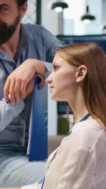 Dikey video Startup yeni katılımcısı ofiste arkadaş ediniyor, makine öğrenme teknolojisini kullanmayı öğreniyor. İş yerindeki neşeli genç kız iş arkadaşlarıyla sohbet ederken yapay zeka öngörüsü modelleri, kamera A kullanıyor.