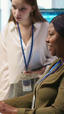 Dikey video gülen başlangıç yöneticisi Küçük Dev 'e makine öğrenme teknolojisini nasıl kullanacağını öğretiyor. Mutlu Afro-Amerikan takım lideri, stajyere yapay zeka öngörüsü modellerini nasıl kullanacağını gösteriyor. Kamera A.