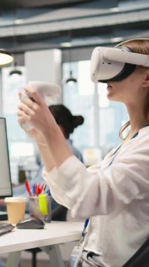 VR gözlük takan dikey video kadın teknisyeni. Başlangıç ofisinde yapay zeka modeli yardımıyla kodlama yapıyor. LLM yardımcı önerilerini kod düzenleyiciye entegre eden sanal gerçeklik kullanan genç kadın