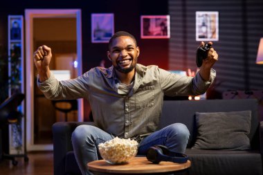 Neşeli, kendine güvenen, video oyunları şampiyonluğunu kazanan genç adam, başarısından memnun ve kutluyor. Neşeli siyahi kişi boş zamanın tadını çıkarıyor ve oyun kazanıyor..