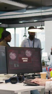 Açılış ofisindeki dikey video programcısı kodlama sırasında uygulama hatalarını düzeltmeye çalışıyor. Yazılım geliştirme ajansında kodlama yaparken bilgisayar hatalarıyla uğraşan genç bir kadın, kamera A