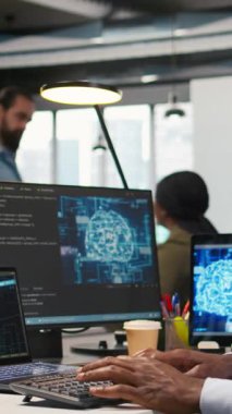 Ofisteki dikey bilgisayar bilimcisi yapay zeka öğrenme sistemlerini iş akışlarını düzene sokacak şekilde entegre ediyor, kulaklıkları takıyor. Afrikalı Amerikalı adam cihazlar üzerinde yapay zeka kullanıyor, dinliyor.