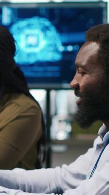 Yapay zeka algoritmalarını kodlarken engelli ve iş arkadaşı sohbet eden dikey video teknisyeni yazılım hatalarını düzeltiyor. Teknisyen bürosunun teknoloji uzmanı tekerlekli sandalye ve iş arkadaşı