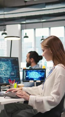 Ofisteki dikey video devi yapay zeka teknisyenine birden fazla cihazda görev yapması ve ekranlardaki ilerlemeyi izlemesi için güveniyor. Genç işçi yapay zeka modelleri geliştirmek için sinirsel ağlar kullanıyor.