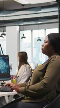 Bilgisayardaki yapay zeka sinir ağı teknolojisini kullanarak performans ve tahminleri optimize eden dikey video yönetmeni. Ofisteki kadın bilgisayar kullanarak yapay zeka eğitimi alıyor.