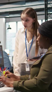 Dikey Video Yöneticisi, genç teknisyene yapay zeka kullanarak yazılımı nasıl geliştireceğini ve nasıl optimize edeceğini öğretiyor. Takım lideri, başkanlık koltuğunda stajyere suni zekanın darboğazı nasıl çözeceği konusunda rehberlik ediyor.