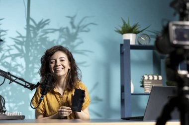 Neşeli etkili sunucu sponsorluk yapan markadan akıllı telefonu sunar, özellikleri analiz eder. İnternet kanalını izleyen teknoloji meraklılarının telefonlarını inceleyen iyimser içerik yaratıcısı,