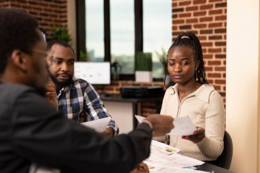 Afrika kökenli Amerikalı kadın ve erkekler şirket toplantılarında mali raporları değerlendiriyorlar. Tuğla duvar çalışma alanındaki meslektaşlarından mali belge alan siyahi kadın çalışanlar.