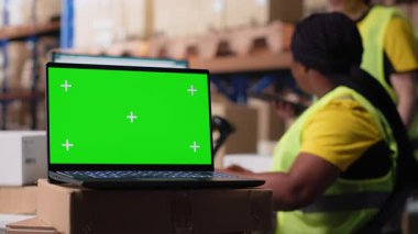 Depo personeli bilgisayar ekranında yeşil ekranın yanında çalışır, endüstriyel depolama odasındaki nakliye etiketleri ve sipariş tamamlama veya e-ticaret envanter sistemlerini yönetir. Kamera B.
