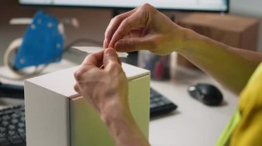 Asyalı bir çalışan nakliye etiketleri takıyor ve takip bilgilerini tarıyor, teslimat sırasında kargo bilgilerini kaydediyor. Depodaki görevleri Hi vis Yeleği ile etiketliyor. Kamera B.