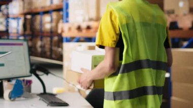 Karton kutulara nakliye etiketleri kaydetmek için tarayıcı kullanan Asyalı bir çalışan. Ekspres teslimat için profesyonel izleme yazılımı. Çevrimiçi büyük iş yerleri alışverişi. Kamera B.