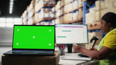 Depo personeli bilgisayar ekranında yeşil ekranın yanında çalışır, endüstriyel depolama odasındaki nakliye etiketleri ve sipariş tamamlama veya e-ticaret envanter sistemlerini yönetir. Kamera A.