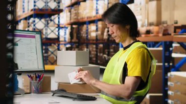 Dağıtım merkezi personeli paketlere yanlış etiketler basıyor ve uyguluyor, bir depoda yelek giyiyor. Siparişleri tamamlamak ve takip etmek için barkod havayolu faturası ve nakliye etiketleri kullanılıyor. Kamera B.