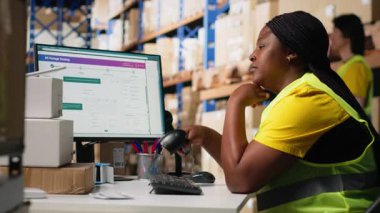 Endüstriyel depolama alanında uzun bir vardiya sonrasında aşırı çalışan Afrikalı Amerikalı kadın ayakta kalmaya çalışıyor. Yorgun personel üyesi. Kamera B.