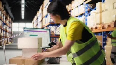 Personel üyesi, sevkiyattan önce barkod izleme bilgilerini tarıyor, büyük ölçekli siparişlerin yerine getirilmesi için depoda çalışıyor. Endüstriyel depolama tesisinde mal dağıtımı. Kamera A.