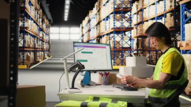 Yelek giyen bir adam endüstriyel depodaki sevkiyat etiketlerinin detaylarını inceler. Depodaki paketlerden gelen paketler ve pürüzsüz ekspres teslimat için takip numaraları. Kamera A.