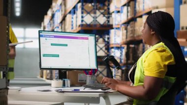 Kadın depo görevlisi barkodları kayıt altına alıyor, kargo etiketlerini ve karton kutulardaki etiketleri tarıyor. E-ticaret için tatmin merkezi dağıtım operasyonları. Kamera B.