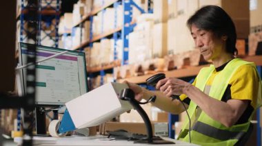 Endüstriyel personel, büyük tatmin merkezinde kutulardaki etiketleri tarıyor, barkod tarayıcısıyla nakliye lojistiği için nakliye etiketleri kaydediyor. E-ticaret için sipariş takibi. Kamera B.