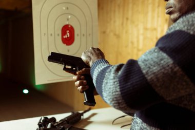 Kapalı alan müşteri silahı ateşleme mekanizması kuruyor. Yakın plan çekiç çekme, dikkatlice silah tutma, ateş etmeye hazırlanma