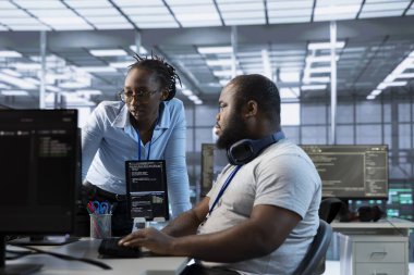 Veri merkezinde bilgisayar üzerinde çalışırken, donanım enerji tüketimini izleyen bir teknisyen yöneticiden yardım istiyor. Ekip lideri, sistem arızalarını kontrol eden bilişim uzmanını denetliyor