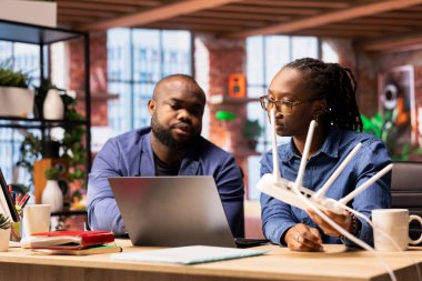 Afrika kökenli Amerikalı bir kadın LAN kablosunu yönlendiriciden çıkarırken partneri de sorun çözme ile ilgili teknik bir kılavuz okuyor. Bağlantı sorunlarını düzeltmek için Wi-Fi sıfırlama işlemi yapılıyor.