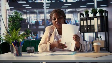 Afrikalı Amerikalı girişimci, video konferansında proje detayları hakkında bilgi paylaşıyor, danışma kuruluyla internette görüşüyor. Genç bayan lider bir strateji için finansmanı arttırmayı umuyor. Kamera A.