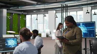 Ofis arkadaşlarının yanında gülümseyen kadın mühendis yazılım uygulamaları geliştiriyor, yapay zeka otomasyonunu birleştiriyor. İşteki geliştiricilerin yanındaki mutlu kadın hata ayıklama uygulamaları, kamera A