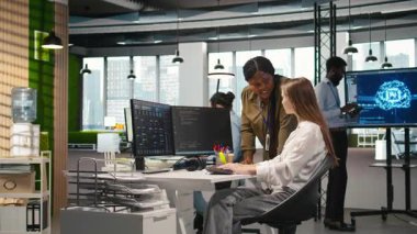 Mutlu yönetici stajyerlerin gelişimini cesaretlendirici kelimelerle överek, beşlik çakarak kutluyor. Gülümseyen takım lideri, genç bayan mühendis ve kamera A için olumlu geri bildirim sağlıyor.