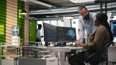 AI kullanarak kodları optimize eden kadın programcıyı alkışlayan memnun ofis yöneticisi. Tatmin olmuş takım lideri ofisteki bilişim uzmanı kamera A tarafından yapılan çalışmalara olumlu geri bildirim sunuyor.