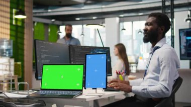 İzole ekran aygıtlarındaki yapay zeka ölçümlerini inceleyen, performans gösterge panellerini izleyen başlangıç ofisi yöneticisi. Sinir ağlarını ayarlayan adam, bilgisayar ve tablet üzerindeki araçları kullanarak, kamera A 'yı ayarlıyor.