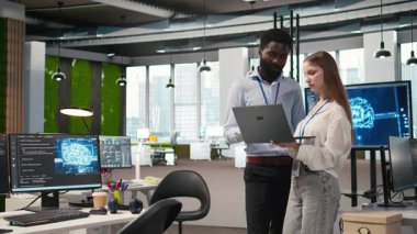 Küçük Dev ve meslektaşı yapay zeka sistem ölçümlerini gözden geçiriyorlar. Performans gösterge panellerini izliyorlar. Teknoloji şirketi programcısı ve genç bayan mühendis sinirsel ağları ayarlıyorlar, kamera A