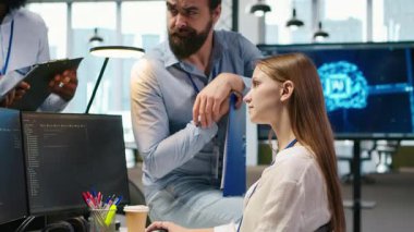 Yeni başlayan arkadaş ofiste arkadaş ediniyor, makine öğrenme teknolojisini kullanmayı öğreniyor. İş yerindeki neşeli genç kız iş arkadaşlarıyla sohbet ederken yapay zeka öngörüsü modelleri, kamera A kullanıyor.