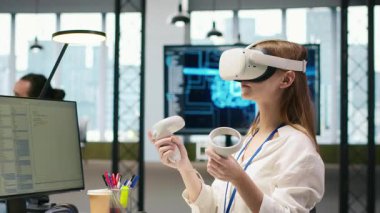 VR gözlük takan kadın teknisyen. Başlangıç ofisinde yapay zeka dili modeli yardımıyla kodlama yapıyor. Sanal gerçeklik kullanan genç bir kadın LLM yardımcı önerilerini kod düzenleyicisi, kamera A 'ya entegre ediyor.