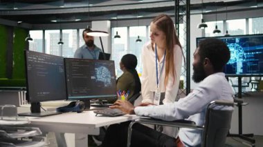 Felç olmuş genç mühendis ve iş arkadaşı ofiste beyin fırtınası yapıyor, yapay zeka ölçümlerini inceliyor. Tekerlekli sandalyedeki küçük dev ve meslektaşı konuşuyor, sinirsel ağları PC, kamera A kullanarak ayarlıyorlar.