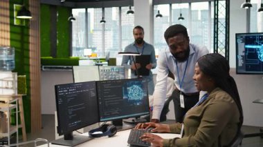 Ofisteki neşeli programcılar, Al ile sürekli tekrarlanan görevleri otomatikleştirerek sohbetin tadını çıkarıyorlar. Mutlu iş arkadaşları sohbet ediyor, yapay zekayı kullanarak uzun metrajlı uygulamaları hızlandırıyor, kamera A