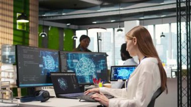 Yüksek teknoloji firma ofisinde bilişim uzmanı yapay zeka modelleri geliştirmek için sinirsel ağlar kullanır. Kadın mühendis, aygıtlar üzerinden görevleri, ekranlardaki ilerlemeyi, kamera A 'yı izlemek için yapay zeka kullanır.