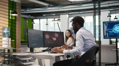 Ofisteki programcı kritik hata uyarısını düzeltmek için iş arkadaşlarından yardım istiyor. BT çalışanı ve meslektaşları, bilgisayar hatasının nasıl düzeltileceği konusunda fikir alışverişinde bulunuyorlar.