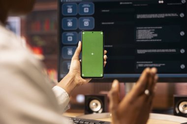 Ofiste bilgisayar ekranında izole ekran akıllı telefonu ve AI LLM sohbet robotu kullanan bir kadın. Model telefonu tutan kişiye yakın çekim sırasında ekranda yapay zeka sohbet robotu kullanılıyor.