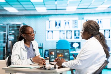 Genç bir hastayla rutin bir kontrol yapan kadın doktor teşhis ve tedavi seçeneklerini radyoloji taramalarıyla analiz ediyor. Profesyonel bir klinikte sağlık hizmeti verileri.