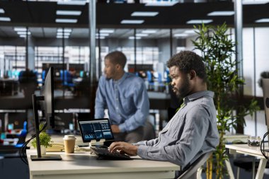 Güvenilir siyah genel müdür ofiste birden fazla iş yapıyor ve bilgisayarındaki idari görevleri çözüyor. Stratejik kararlar alırken belgelerin gözden geçirilmesi ve teslim tarihlerinin tutturulması.