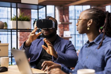 Siyahlar, VR ve AI 'ı günlük rutinlerine entegre eder. Adamın üç boyutlu deneyimi vardır. Dizüstü bilgisayardaki metaevren içindeki animasyonu yöneten genç odaklı kadın..