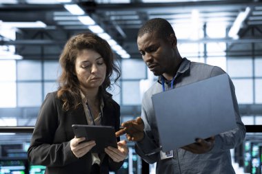 Veri merkezindeki sistem yöneticileri aygıtları kullanıyor, güvenlik yamalarını çalıştırıyor, güvenlik duvarı yapılandırmalarını doğruluyor. Ekip çalışması bilişim uzmanları sunucu merkezinde ekipman savunmasızlığı taraması yapıyor