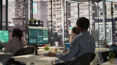 Erkek yönetici analist finansal bir rapor hazırlar ve verileri gözden geçirir, örgütsel ilerleme için bir öngörü geliştirir. Siyahi adam görev yönetimi ve strateji planlaması yapıyor. Kamera B.