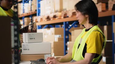 Paket takip ve sipariş işlemleri için depo arz ve talep işlemlerini yapan işçiler, sevkiyat detaylarını bilgisayar monitöründen kontrol ediyorlar. E-ticaret deposu. Kamera B.