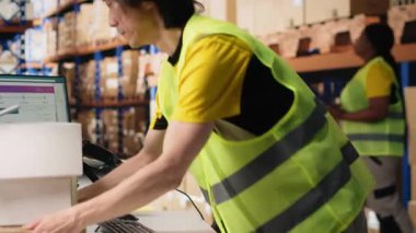 Personel üyesi, sevkiyattan önce barkod izleme bilgilerini tarıyor, büyük ölçekli siparişlerin yerine getirilmesi için depoda çalışıyor. Endüstriyel depolama tesisinde mal dağıtımı. Kamera B.