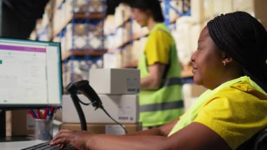 Engelli Afrikalı Amerikalı işçi, dağıtım merkezindeki sipariş paketini izlemek ve yazılım bilgilerini takip etmek için havayolu fatura numaralarını kullanıyor. Sevkiyat operasyonlarını yönetiyorum. Kamera A.